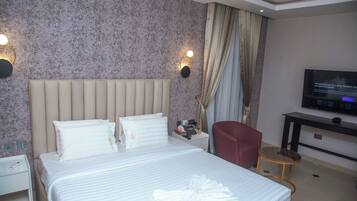 A hotel room with a bed, a TV, a desk, and a chair.