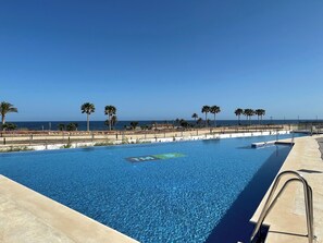Una piscina azzurra e trasparente con vista sull'oceano e su palme.