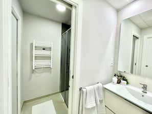 Un bagno con lavandino bianco, uno specchio e un portascopevoli.