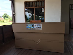 A reception desk with a window, a sign indicating 'RECEPTIONIST,' and a poster with resort information. - Pelangi Lake Resort and Hotel Belitung (Tanjung Pandan)