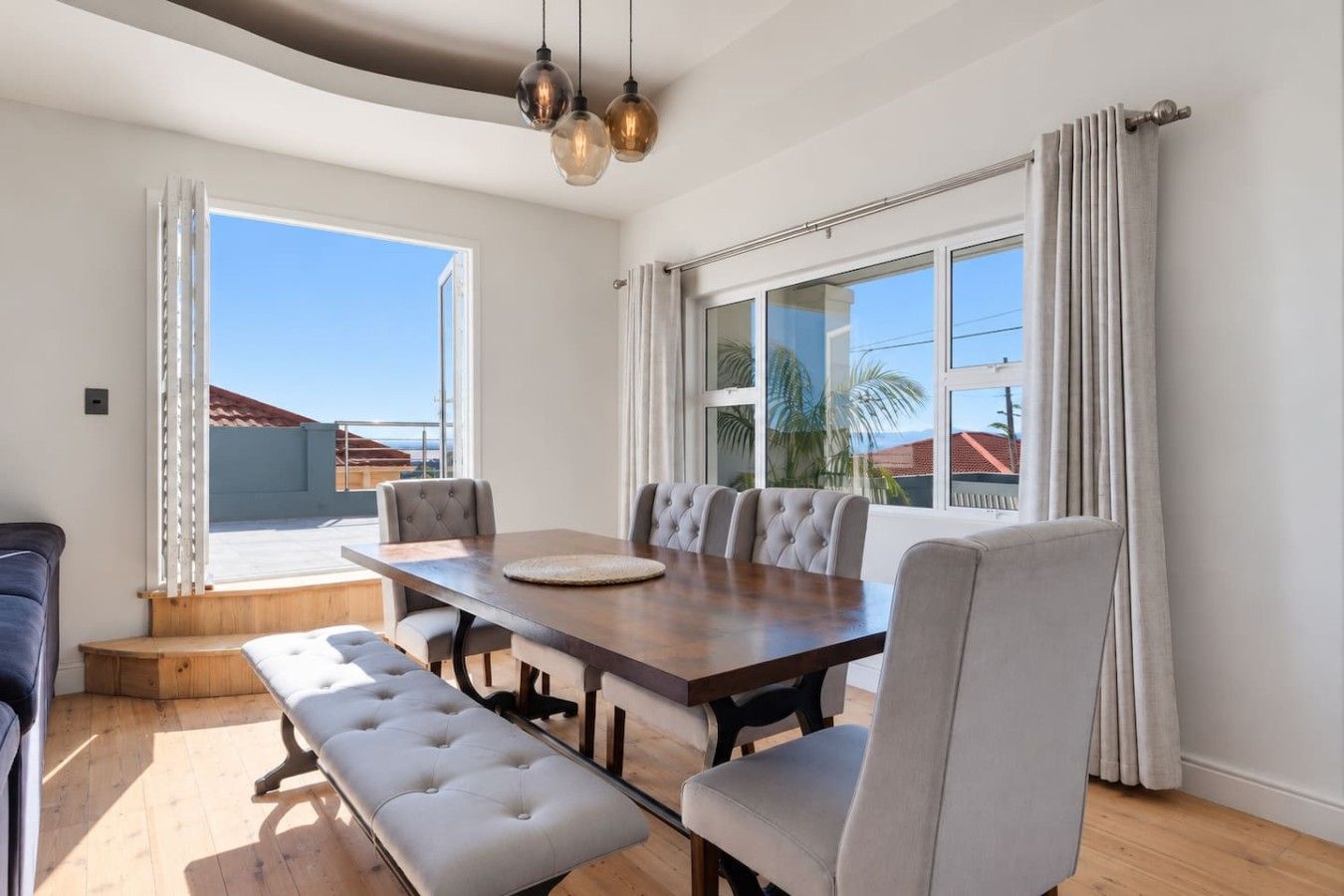 A dining area with a wooden table, cushioned chairs, and a bench.