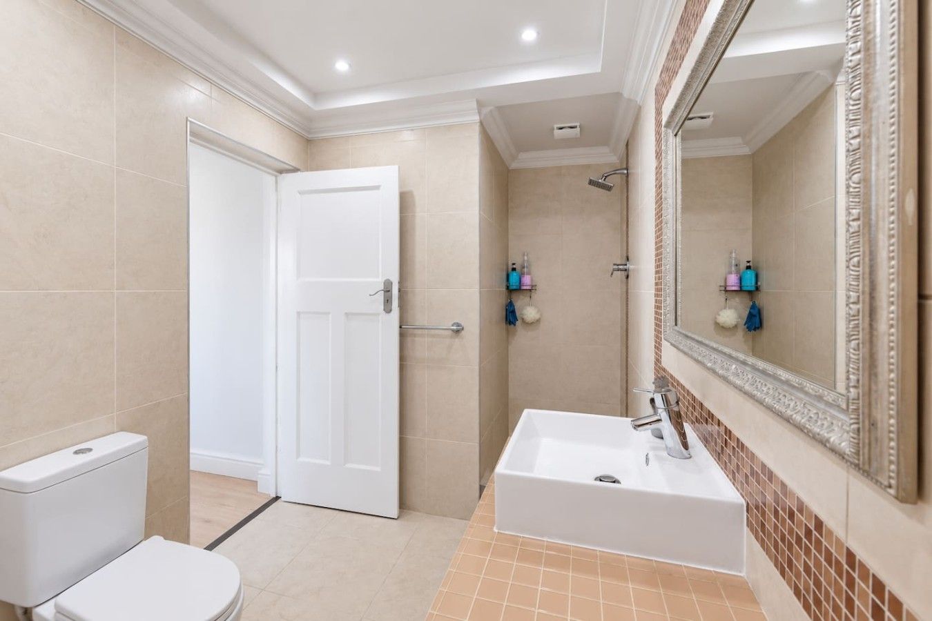 A bathroom with a white toilet, a sink with a mirror, and a shower area.