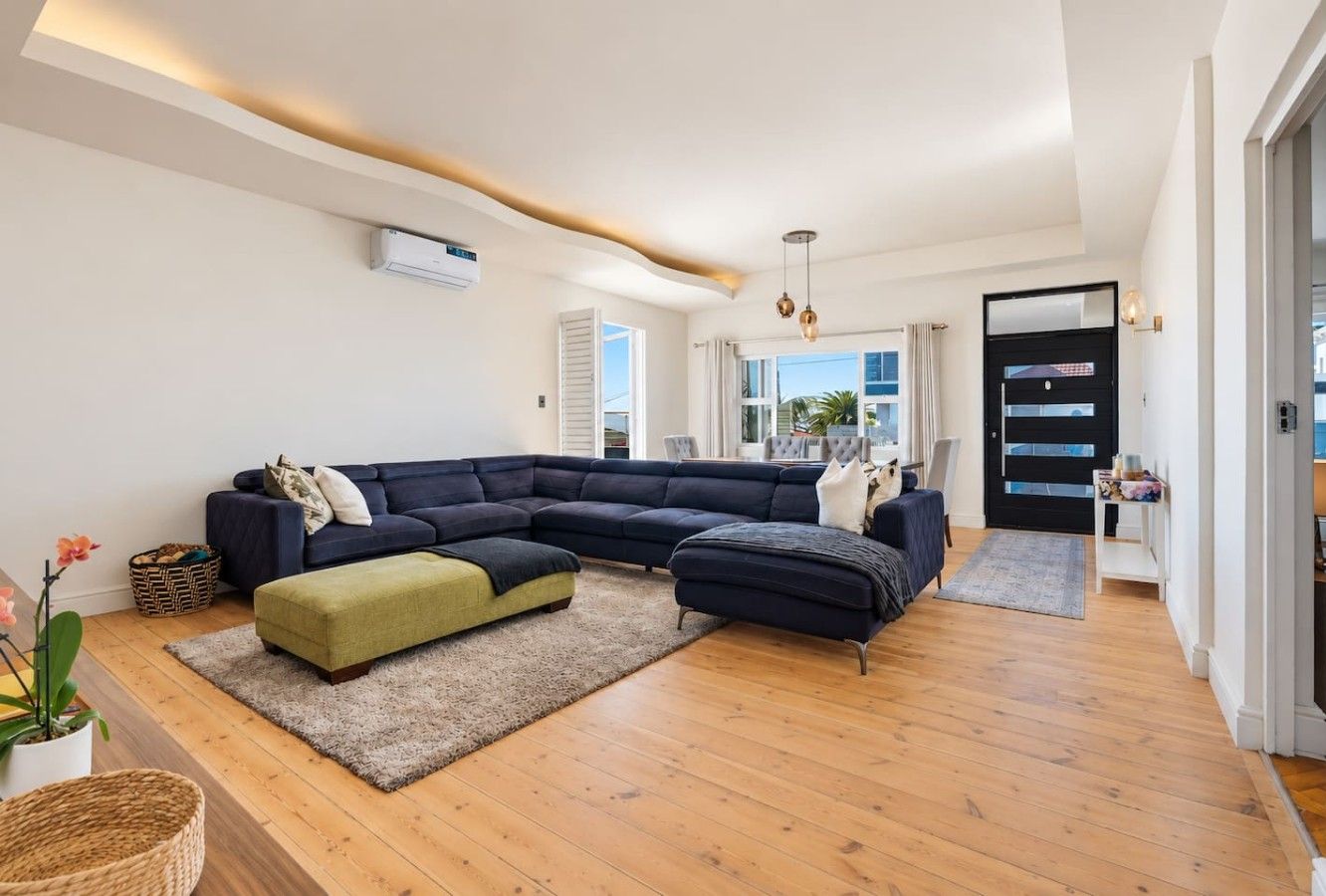 The Relaxation Lounge: An expansive navy sectional invites guests to stretch out and unwind. A contrasting olive ottoman, timber flooring and soft ambient lighting create a welcoming setting for leisurely afternoons and family gatherings.