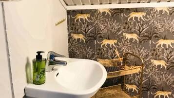 A bathroom with a white sink, a gold vanity, and a patterned wallpaper.