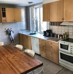 Ett kök med träskåp, diskmaskin, diskho och spis.