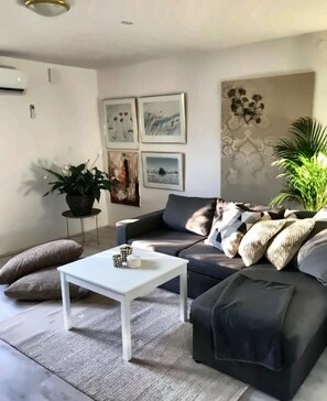 Ett vardagsrum med en soffa, ett soffbord och en krukväxt.