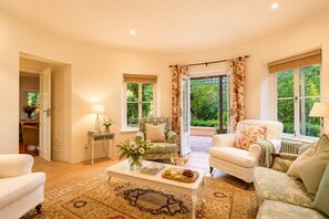 A spacious living room with a large window, a coffee table with books and flowers, and two sofas. - Welgelee Silos - Surrounded by vineyards, gardens and mountain views (Cape Town)