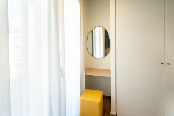Une pièce avec un miroir, un banc jaune et une armoire.