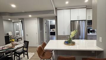 A modern kitchen with a central island, stainless steel appliances, and a dining area with a round table and chairs.