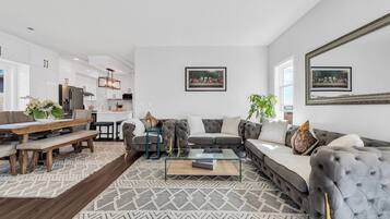 A modern living room with a sofa, coffee table, and a dining area with a bench.
