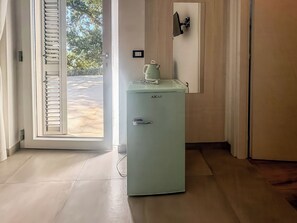 Una habitación con un refrigerador azul claro, una puerta con vidrio ranurado y un enchufe eléctrico fijado a la pared.