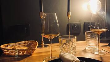 Ein Tisch mit Weinglas, Kerze, Kerzenhalter, Glas, Löffel, Gabel und Serviette.