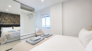 Een moderne hotelkamer met een groot bed, een inloopkast, een raam met uitzicht en een stoel.