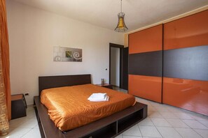 A bedroom with a bed, a bedside table, a hanging light fixture, and a wardrobe with a sliding door. - Sandro (Sicilia)