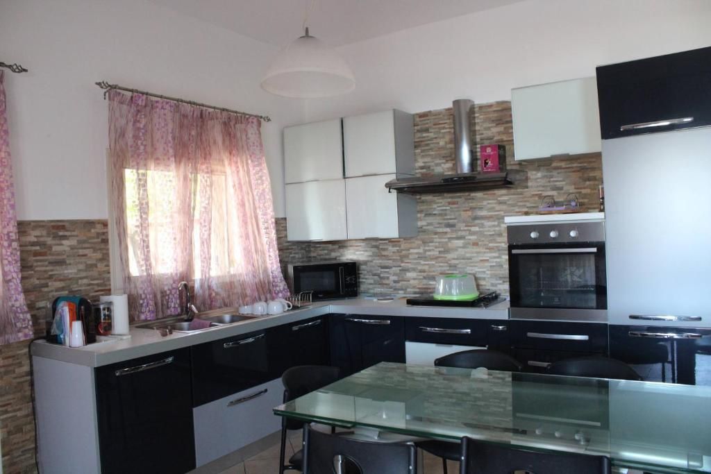 Cozinha moderna com mesa de jantar de vidro, armários pretos, micro-ondas embutido e forno de aço inoxidável.