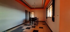 A hallway with a checkered floor, a dining table with chairs, and a window on the right.