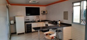 A kitchen with a black countertop, white cabinets, a microwave, and a window. - New Listing (Mateus Leme)