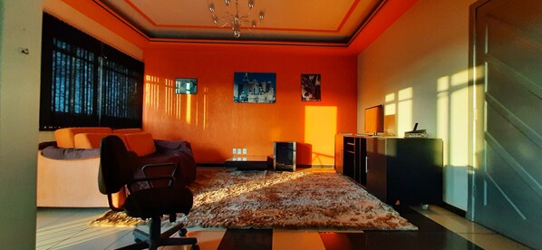 A modern living room with a large window, a sofa, a rug, and a television.