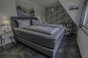 Ein Schlafzimmer mit einem großen Bett, einem Nachttisch mit Lampe und einer Wand mit Muster.