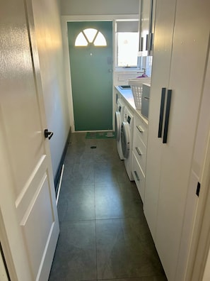 Une buanderie équipée d’un lave-linge, d’un sèche-linge et d’une porte avec une fenêtre.