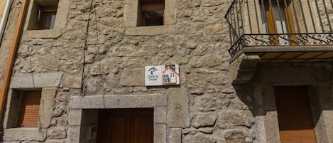 Edifici de pedra amb una porta de fusta i un balcó amb barana de ferro forjat.