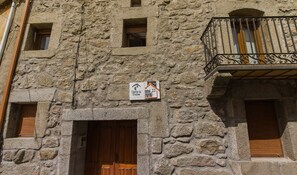 Edifici de pedra amb una porta de fusta i un balcó amb barana de ferro forjat.