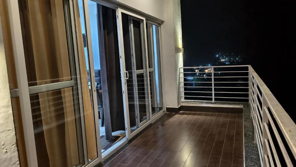 A balcony with a metal railing, a tiled floor, and a view of the city at night.