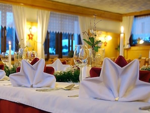 A table set with white napkins, wine glasses, and cutlery, with a candle and a decorative branch in the center. - Cafe Pension Kitzer (Haus im Ennstal)