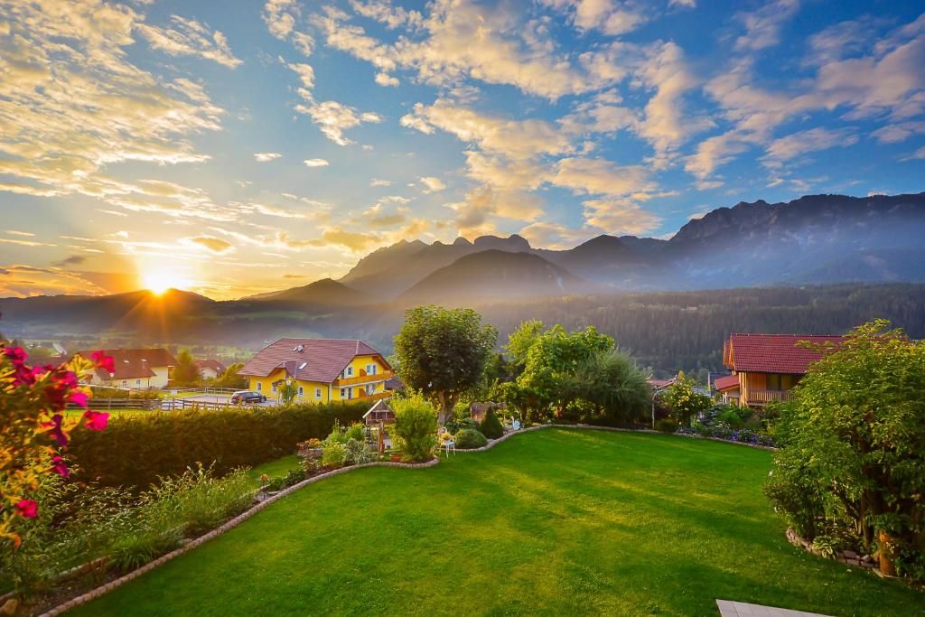 A residential area with houses, a well-maintained lawn, and mountains in the background.