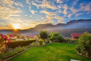 A residential area with houses, a well-maintained lawn, and mountains in the background. - Cafe Pension Kitzer (Haus im Ennstal)