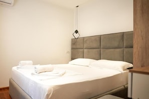 Una habitación de hotel con una cama, cabecera y lámpara colgante.