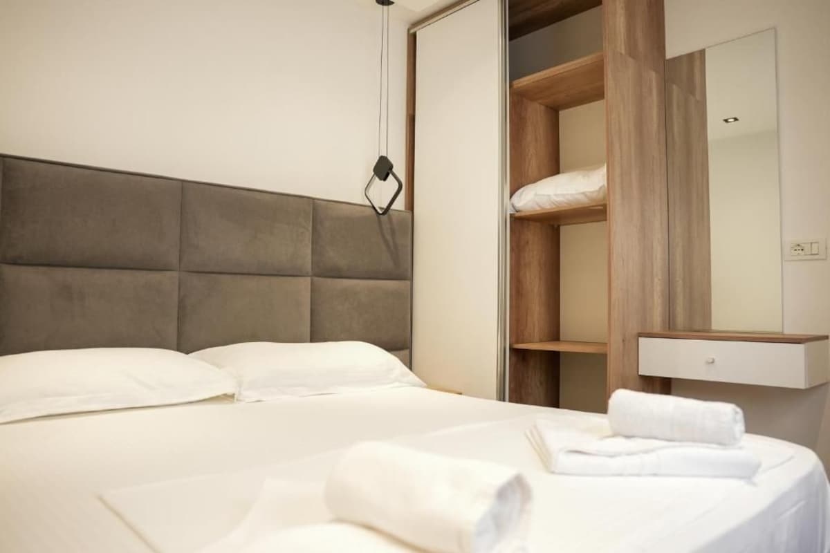 A hotel room with a bed, a wardrobe, and a mirror.