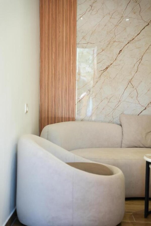 Una sala moderna con un sofá curvo, una pared decorativa de madera y una pared con diseño de mármol.
