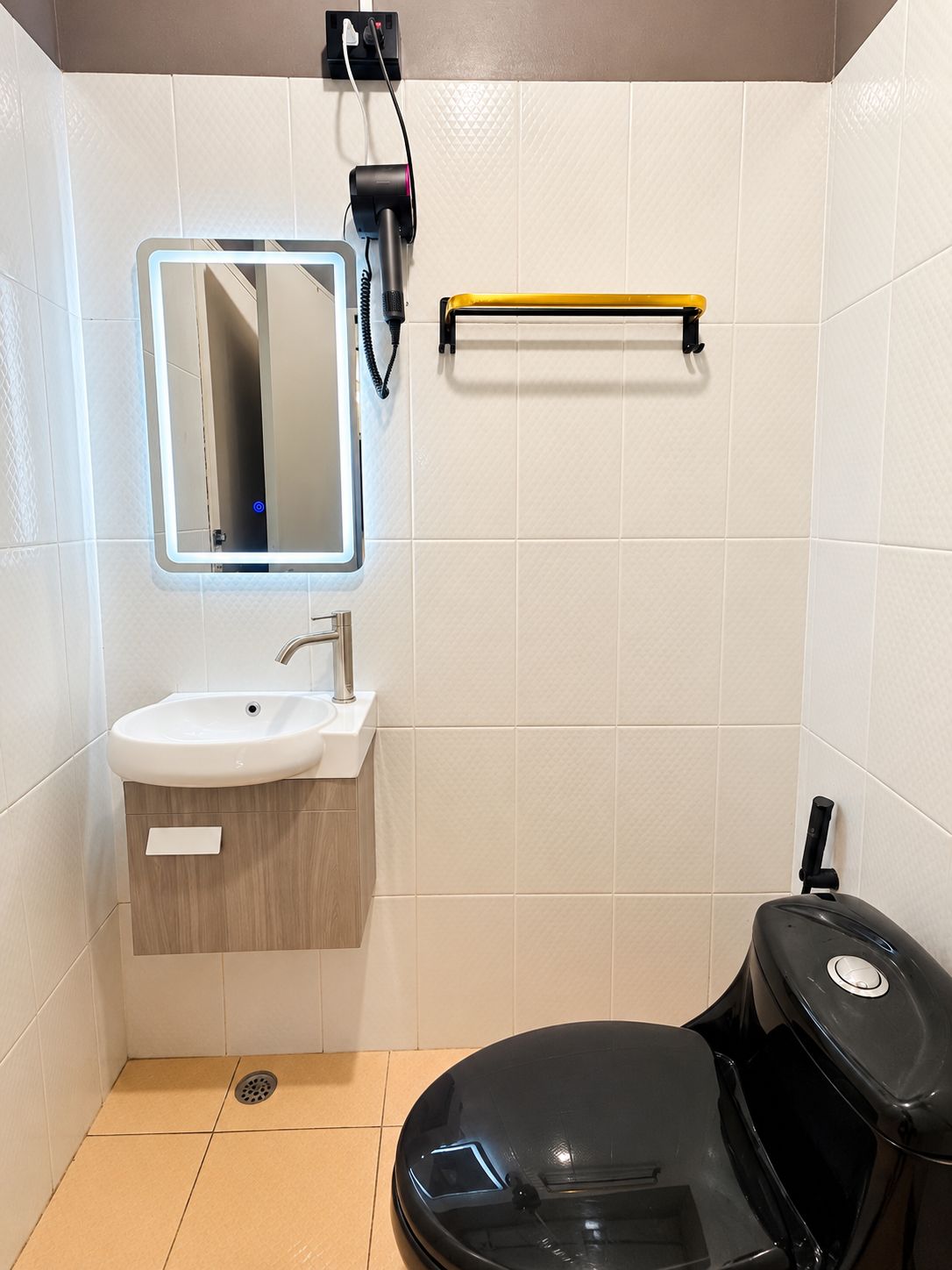 A bathroom with a white sink, a mirror, a black toilet, and a towel rack.