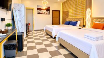 A hotel room with two beds, a desk with a chair, a trash bin, and a wall-mounted TV.