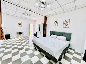 Habitación de hotel con piso a cuadros, cama con ropa blanca, cabecera verde y dos obras de arte colgadas en la pared.