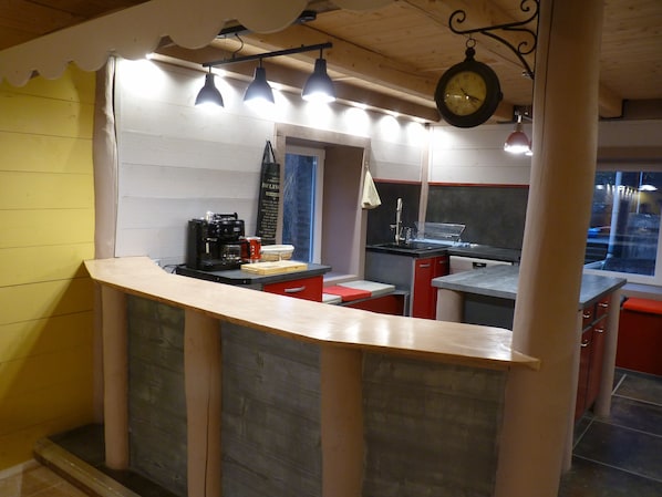 A kitchen with a wooden counter, a coffee machine, and a hanging clock.
