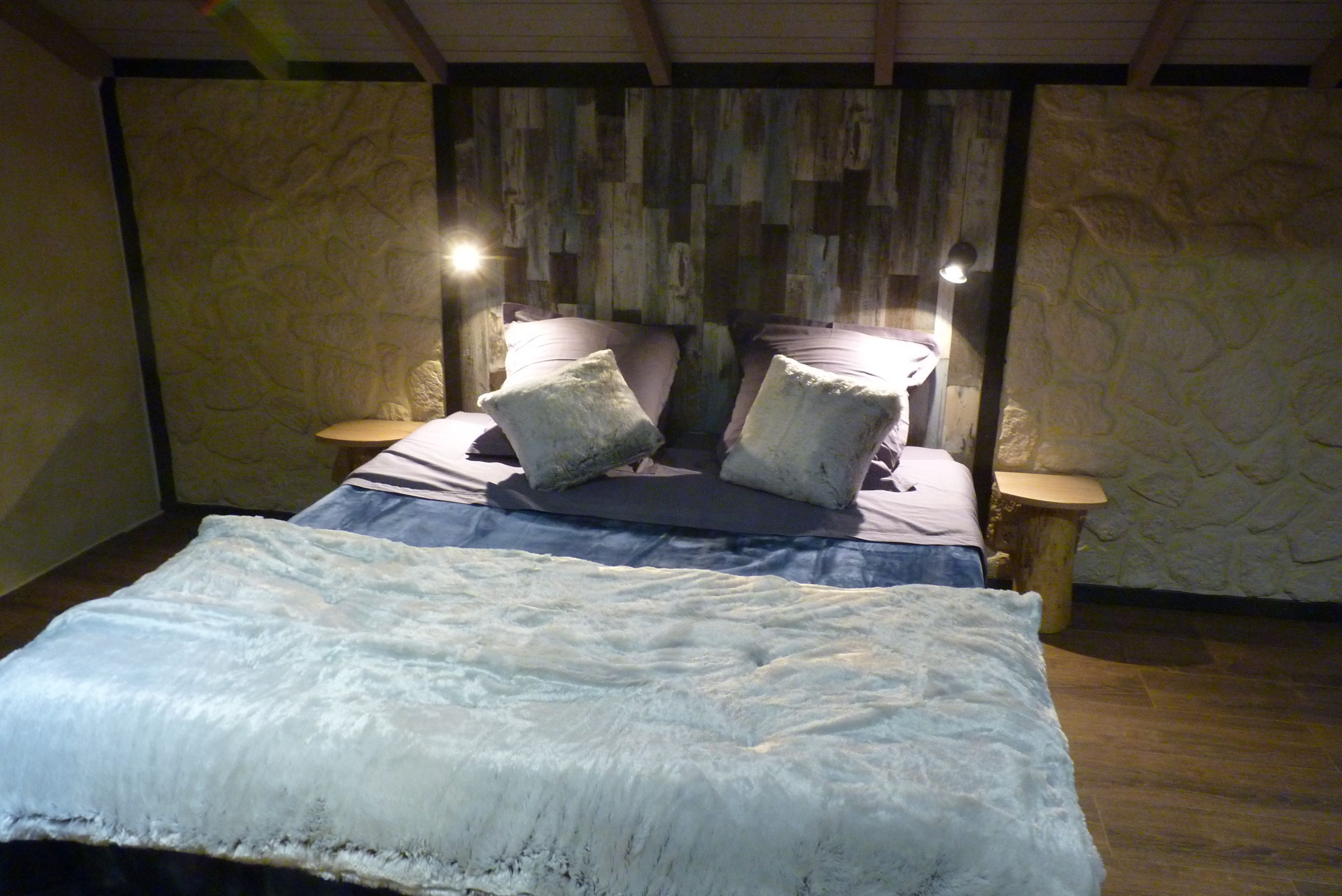 Un dormitorio con una cama, dos mesitas de noche y una pared decorada con paneles de madera.