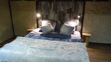 Un dormitorio con una cama, dos mesitas de noche y una pared decorada con paneles de madera.