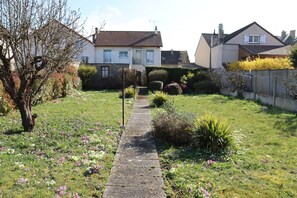 A residential garden with a pathway leading to a house. - Cottage 'Le P'tit Martin' (Mainvilliers)