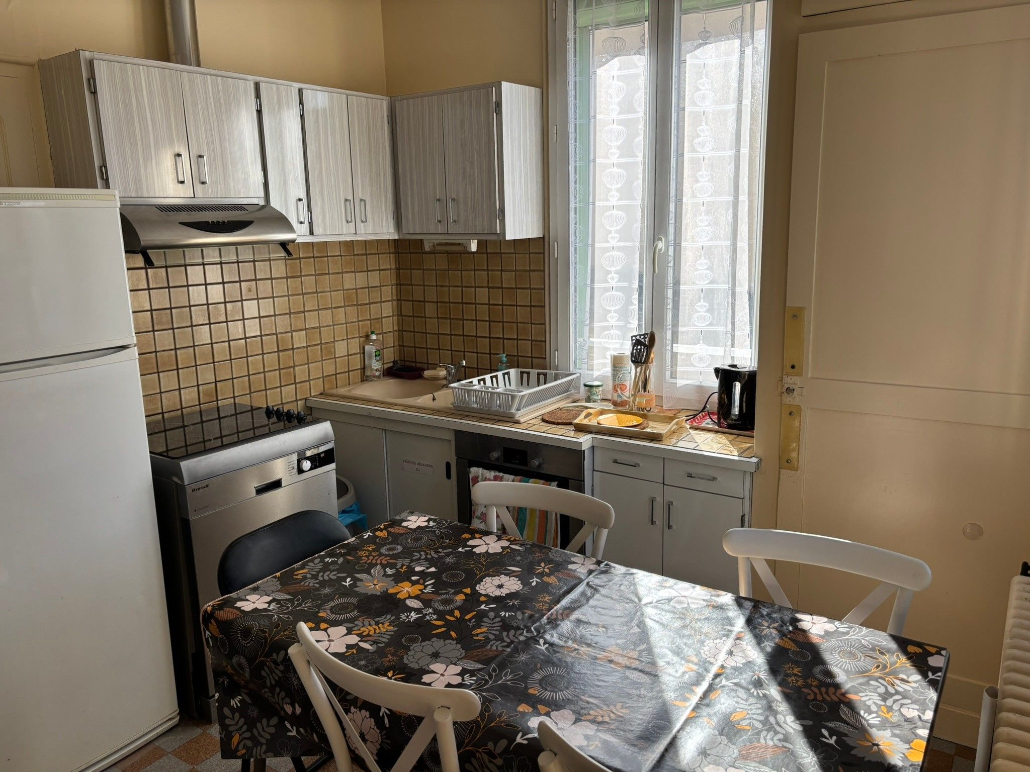Cozinha compacta com geladeira, fogão e mesa de jantar com cadeiras.