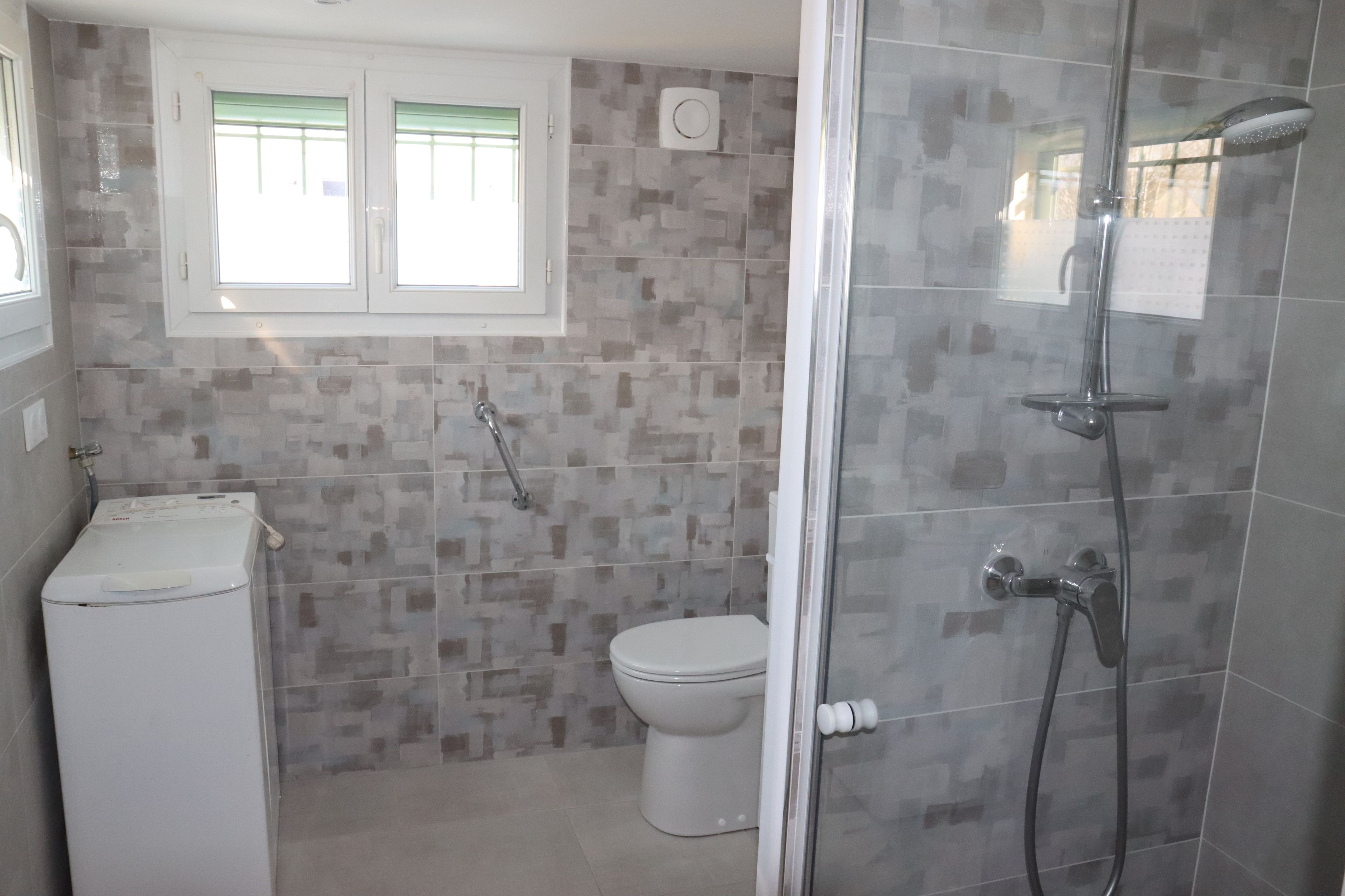Une salle de bain avec douche, toilettes et machine à laver.