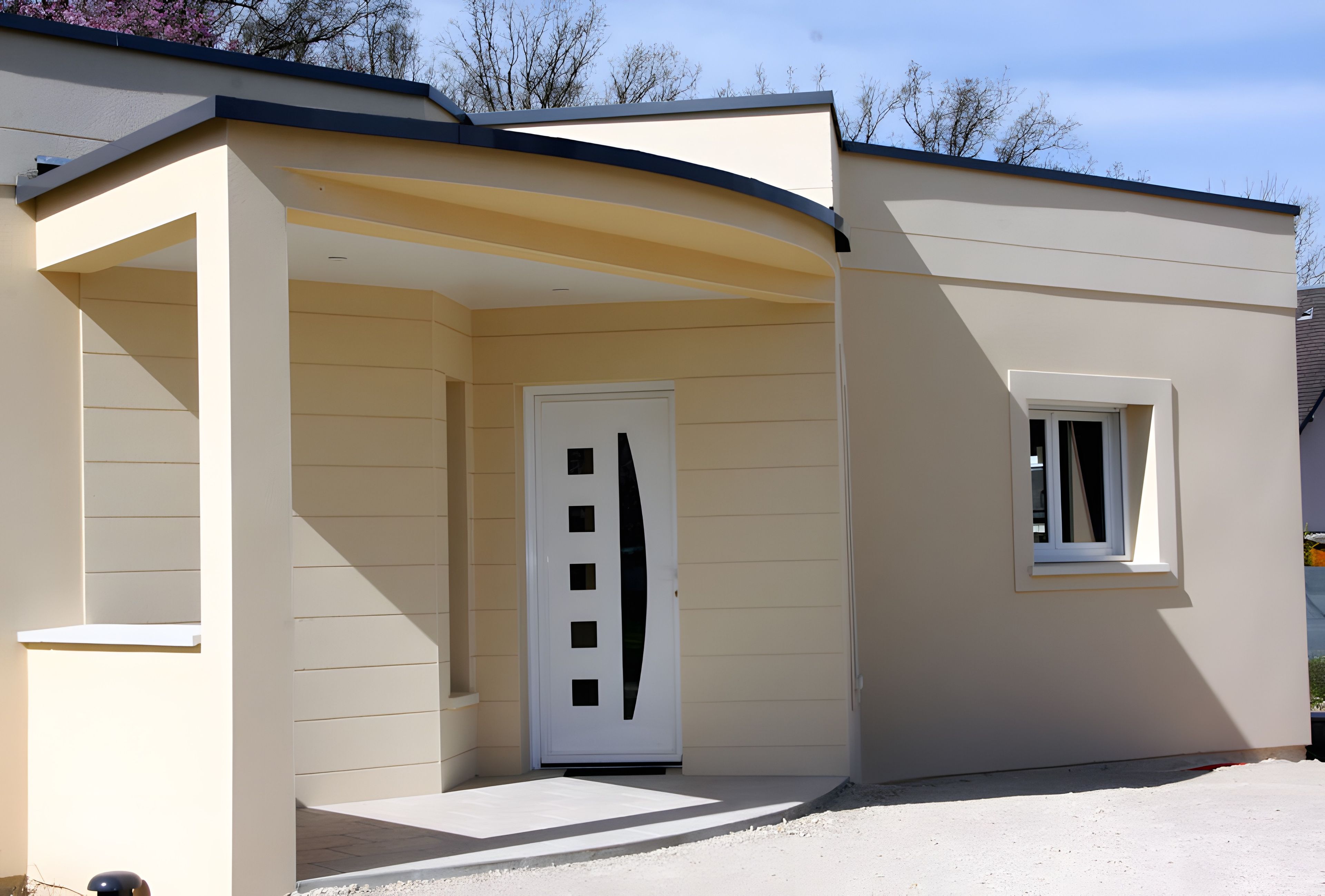 Ein Gebäude mit einer beige farbenen Fassade, einer weißen Tür mit schwarzem Streifen und einem kleinen Fenster.