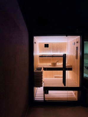 A sauna with wooden walls and benches, a visible heater, and a clock on the wall. - Terrace with sauna and hot tub in Villamagna (Villamagna)