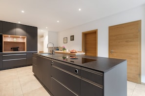 A modern kitchen with dark cabinetry, a central island, and wooden accents.
