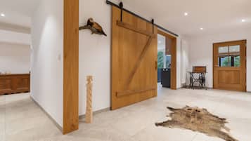 A spacious room with a large wooden sliding door, a rustic wooden sculpture, and a fur rug on the floor.