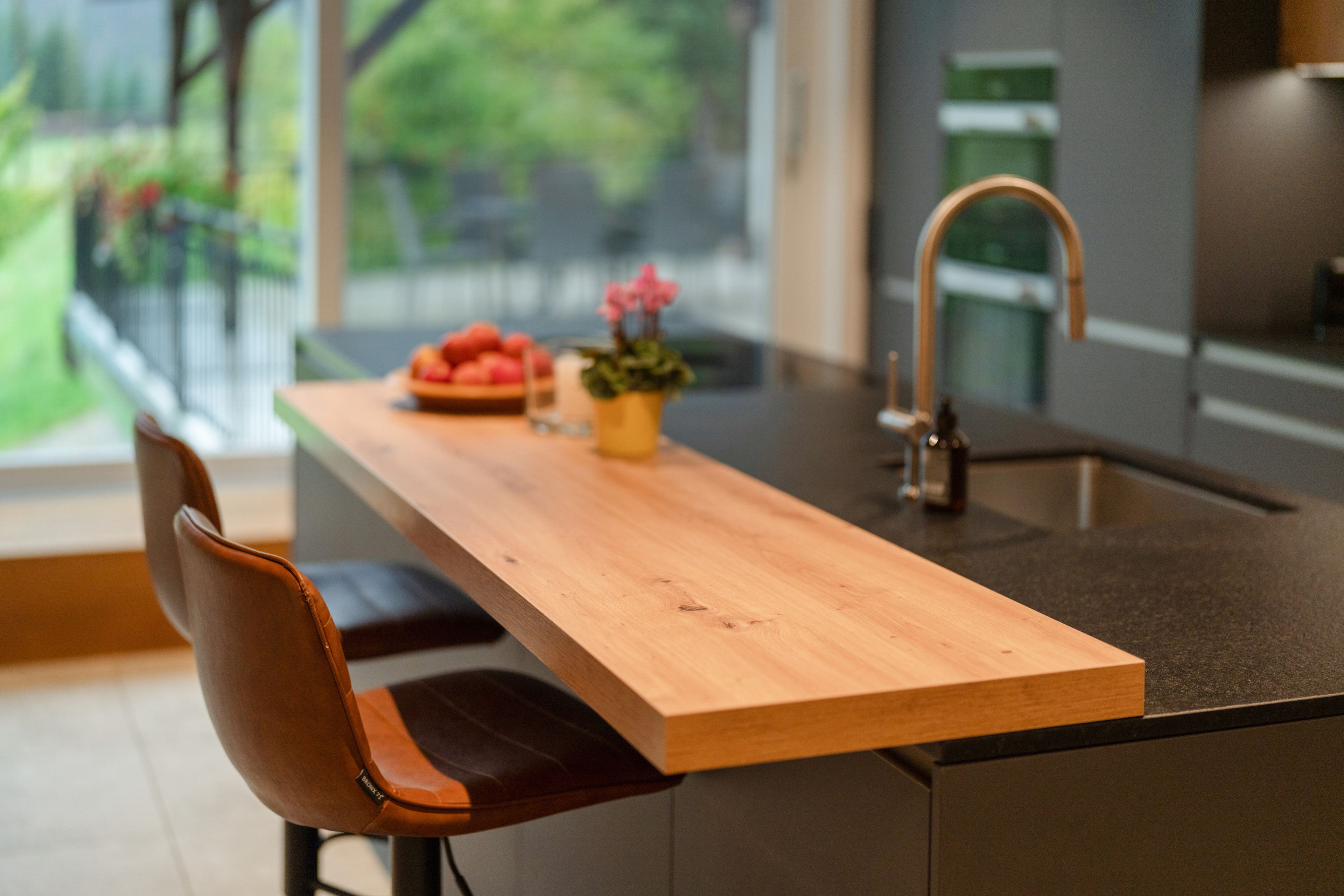 A modern kitchen with a wooden countertop, a sink, and a chair.