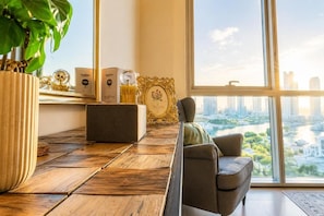 En moderne stue med sofa, sofabord og udsigt over bybilledet gennem store vinduer.