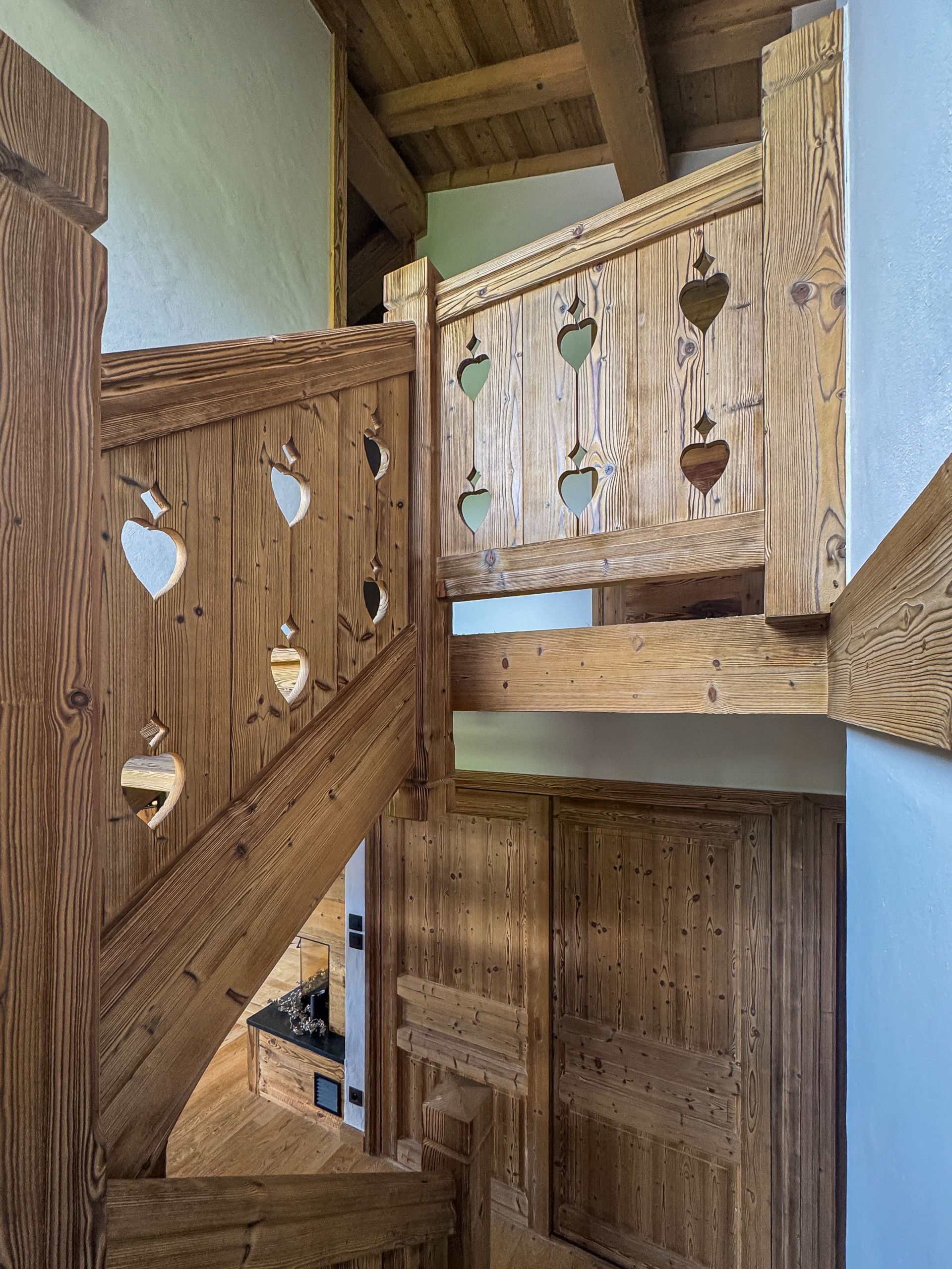Un escalier en bois orné de découpes en forme de cœur et doté d’une rampe en bois.