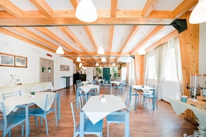 Une salle à manger spacieuse avec des poutres en bois, plusieurs tables et des chaises.